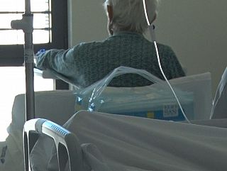 paziente su una sedia in camera d'ospedale guarda dalla finestra