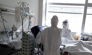 infermieri in tenuta anti Covid in ospedale attorno al letto di un paziente