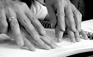 mani di adulto e bambino leggono in braille