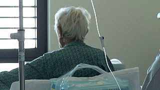 paziente su una sedia in camera d'ospedale guarda dalla finestra