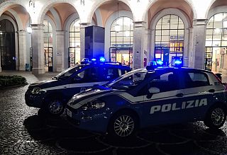 Due auto della polizia con lampeggianti accesi di notte di fronte alla stazione