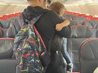 Un padre con in collo il figlio nella cabina di un aereo