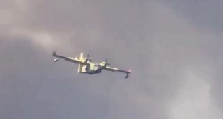 Un canadair fende le colonne di fumo