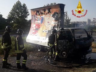 Il furgone incendiato e i vigili del fuoco al lavoro
