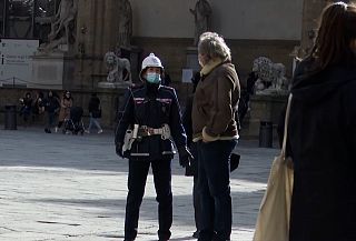 Un vigile urbano e passanti con le mascherine
