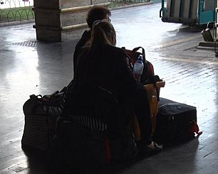 turisti seduti sui bagagli alla stazione