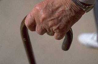 mano di anziano impugna un bastone da passeggio