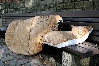 Un senzatetto dorme su una panchina