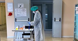 infermiere in tenuta anti Covid nel corridoio di un ospedale con termometro in mano