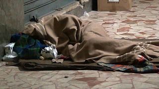 un senzatetto dorme sdraiato sul marciapiede