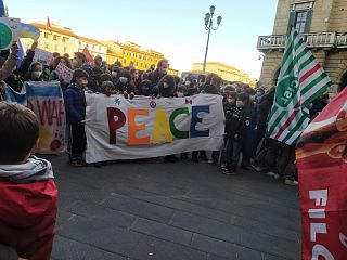Gente con bandiere dei sindacati e uno striscione colorato con scritto Peace