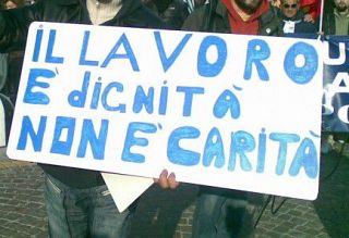 Un cartello esposto durante una manifestazione con la scritta "Il lavoro è dignità non carità"