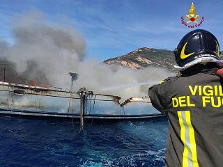 vigili del fuoco mentre spengono incendio sulla barca in mare