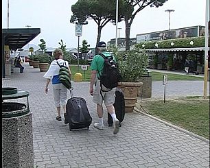 piazzale esterno aeroporto di Pisa, turisti con valige