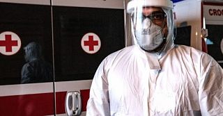 infermiere usca in tenuta anti covid davanti a un'ambulanza