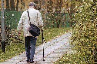 anziano cammina col bastone