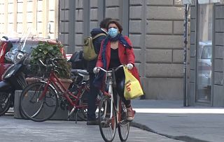 Una donna in bicicletta con la mascherina 